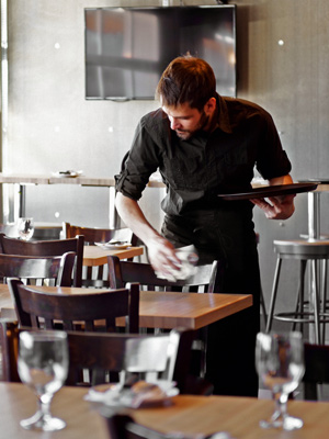 Waiter cleaning and dressing tables