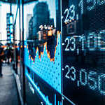 Stock market graph and numbers merge with the blur of city lights.
