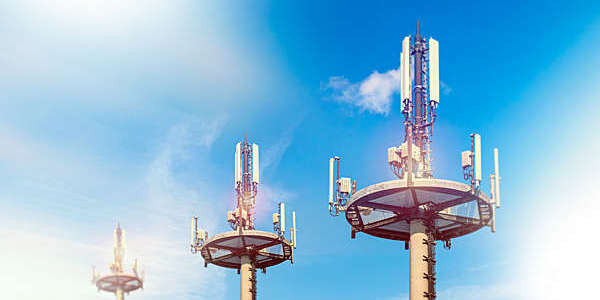 Top section of three telecommunication cell towers viewed against blue skies.