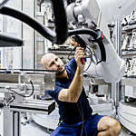 Man working on an industrial robot at a manufacturing site.