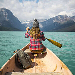 A young woman canoeing on a scenic mountain lake